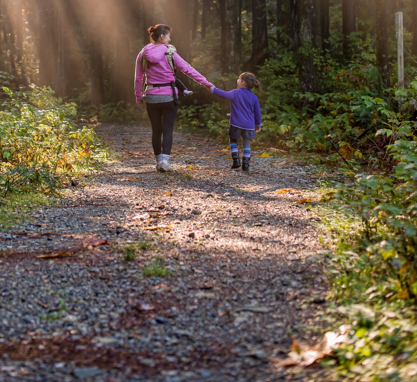 Mother enjoying a hike through the forest with young girl.
